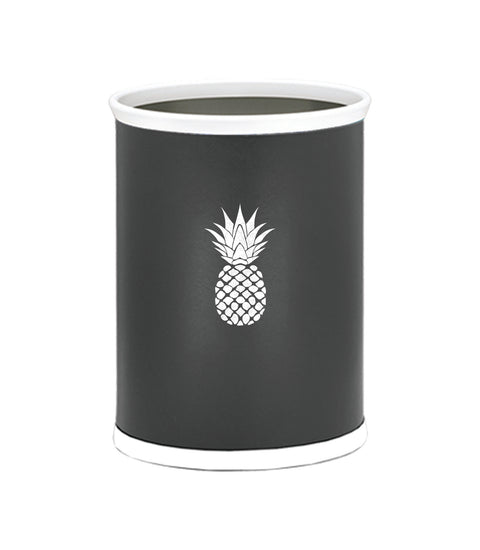 Black | Oval wastebasket featuring smooth leatherette and a white pineapple design adding a fresh touch to a coastal-themed room.