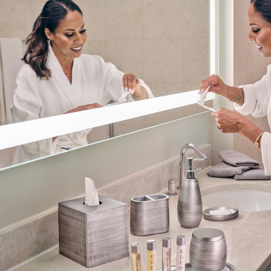 Silver | Woman in a bathrobe using a tissue in a bathroom with modern decor.