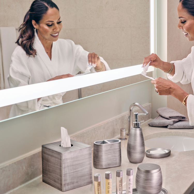 Silver | Woman in a bathrobe using a tissue in a bathroom with modern decor.