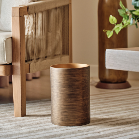 Gold | Metallic wastebasket sitting on the floor next to a chair.