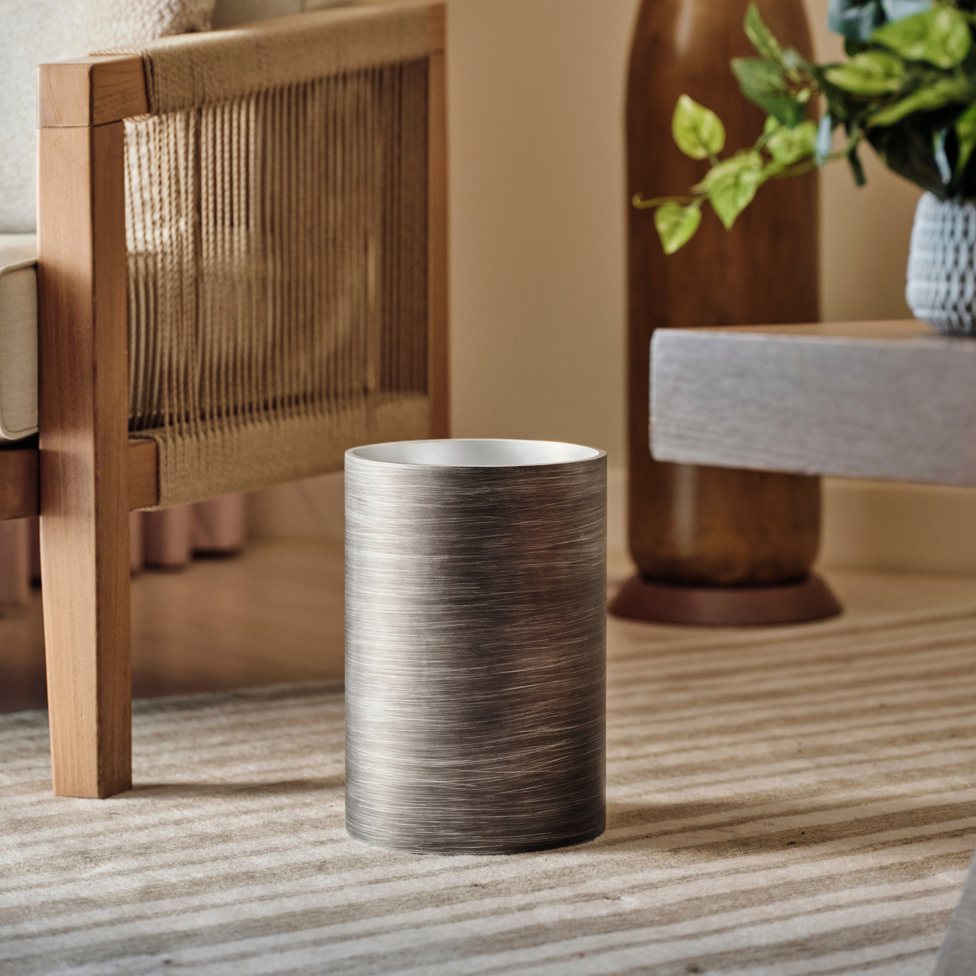 Silver | Metallic wastebasket styled on a striped rug in an apartment.
